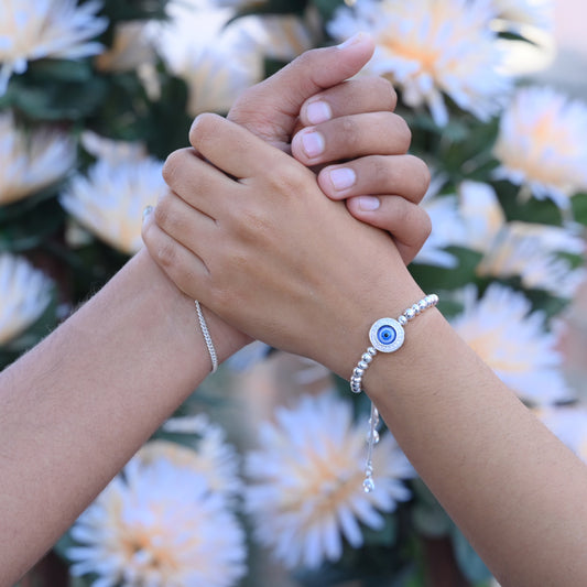 Silver bracelet with floral design and evil eye stone for spiritual protection.