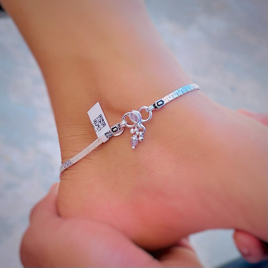 Silver anklet adorned with vibrant stones and delicate leaf designs.