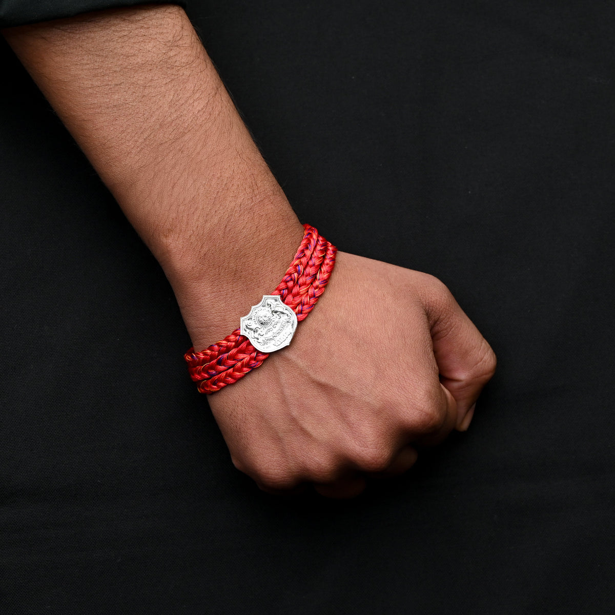 Traditional silver dhaga moli with royal crest in the center