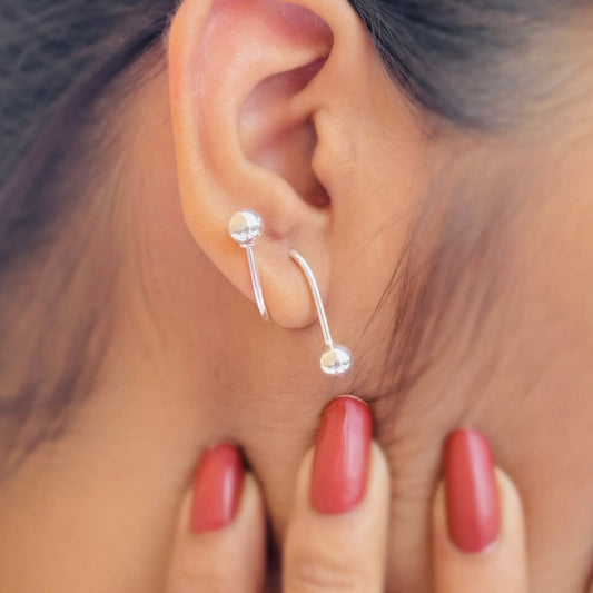 Sleek silver double sphere climber earrings with minimalist design.