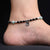 Green evil eye charm on silver heart anklet.