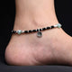 Green evil eye charm on silver heart anklet.