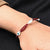 Stylish silver bracelet with red beads and a central evil eye design.