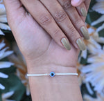 Load image into Gallery viewer, Silver bracelet with blue evil eye charm for fashionable protection.
