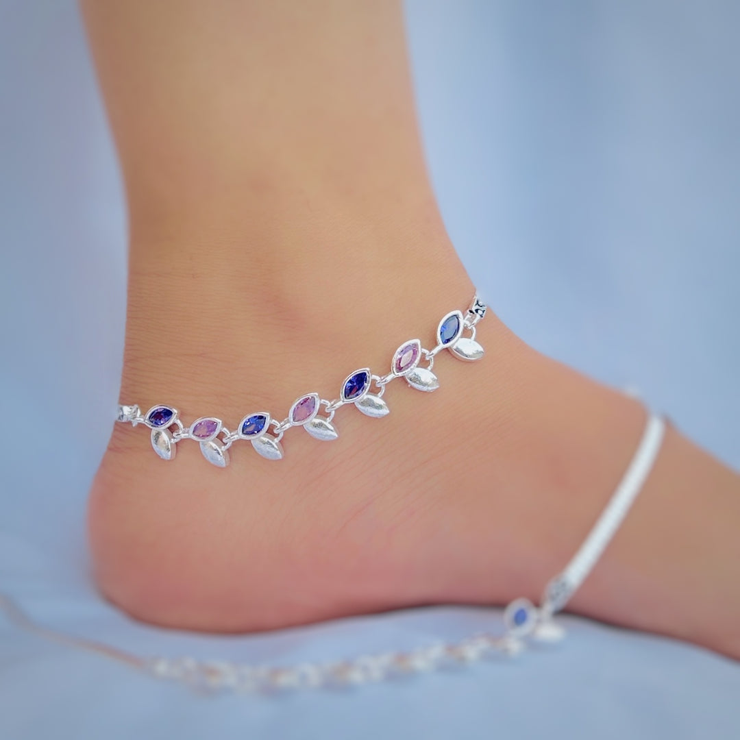 Silver anklet featuring blue and pink stones, leaf patterns, and buds.