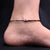 Silver anklet with protective evil eyes and black beads.