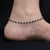 Elegant silver anklet with black beads and chain detail.