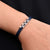 Elegant silver bracelet featuring a blue arrow motif with connecting elements.